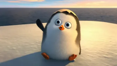 Small cute baby penguin with an eggshell on top of its head waving